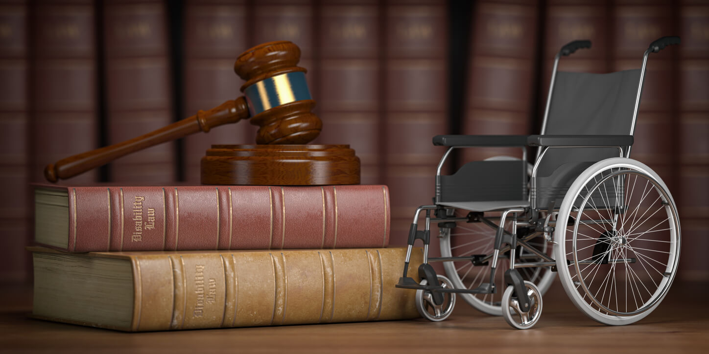 A wheelchair sitting beside two books about Social Security Disability Law and a judge's gavel.