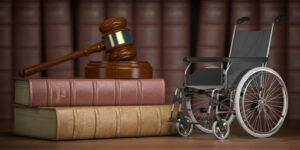 Judge's gavel sits atop two stacked books resting next to a miniature wheelchair