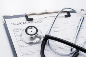A stethoscope sitting on top of a clipboard holding a blank medical record.