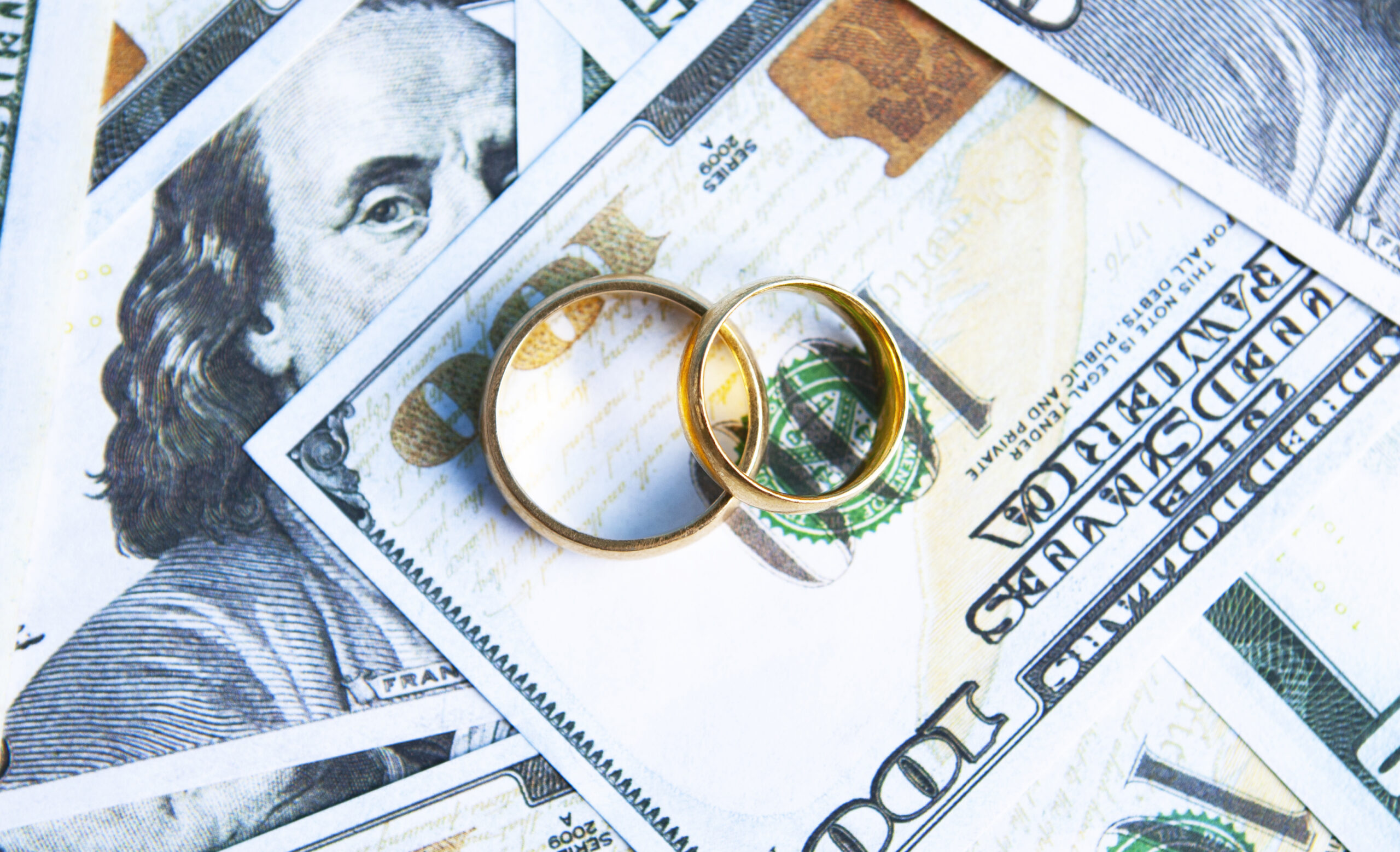 wedding rings laying on top of money